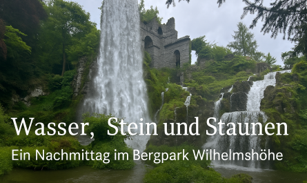 Blick auf den großen Wasserfall am Aquädukt im Bergpark Wilhelmshöhe in Kassel: Das Wasser stürzt aus einer künstlichen Ruine inmitten üppiger Vegetation hinab, während der Titel „Wasser, Stein und Staunen – Ein Nachmittag im Bergpark Wilhelmshöhe“ dezent am unteren Bildrand eingeblendet ist.